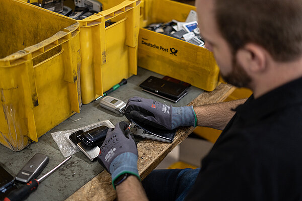 An employee at AfB is disassembling a mobile phone