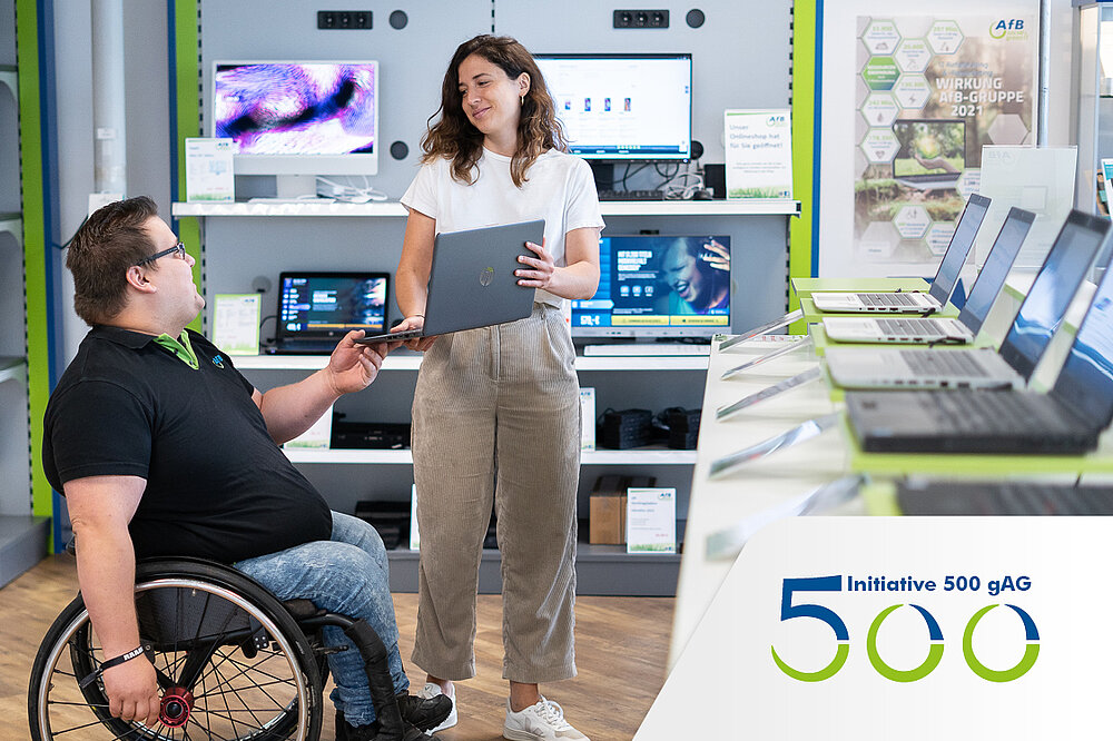 Eine Frau übergibt einem Mann im Rollstuhl einen Laptop einem Hardware-Shop.