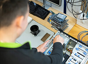 Mitarbeiter repariert einen gebrauchten Laptop für die Wiedervermarktung.