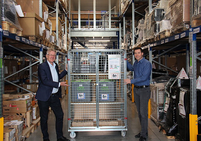 Die beiden AfB-Geschäftsführer Daniel Büchle und Paul Cvilak im Lager der Firmenzentrale. Zwischen den beiden befindet sich ein Gitterwagen.