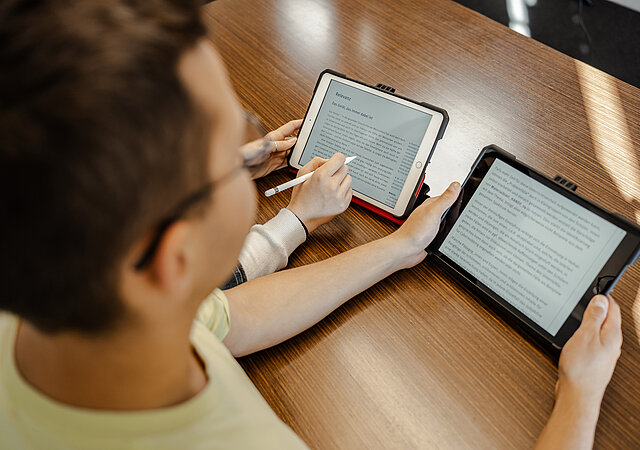 Schüler liest Text auf Tablet im Schulunterricht.