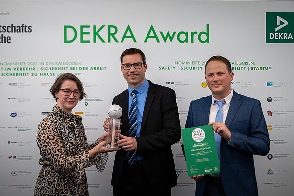 Yvonne Zwick, Daniel Büchle und Nicolai Gräff stehen nebeneinander. Daniel Büchle hält mit Yvonne Zwick den Dekra Award 2022.