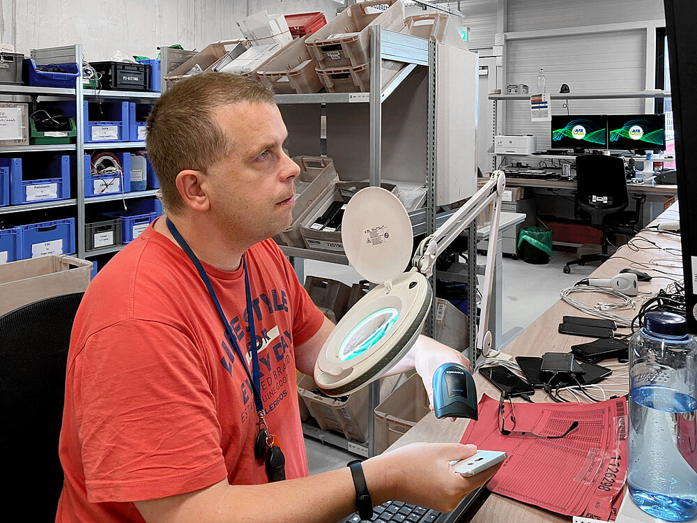 Mann in rotem T-Shirt erfasst Mobilgeräte vor der Datenlöschung