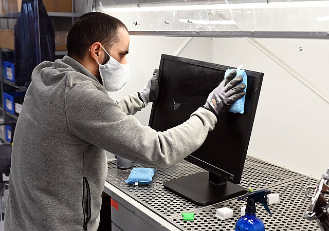 AfB employee cleans monitor before remarketing